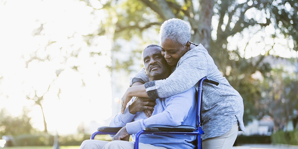 a woman standing behind a man in a wheelchair